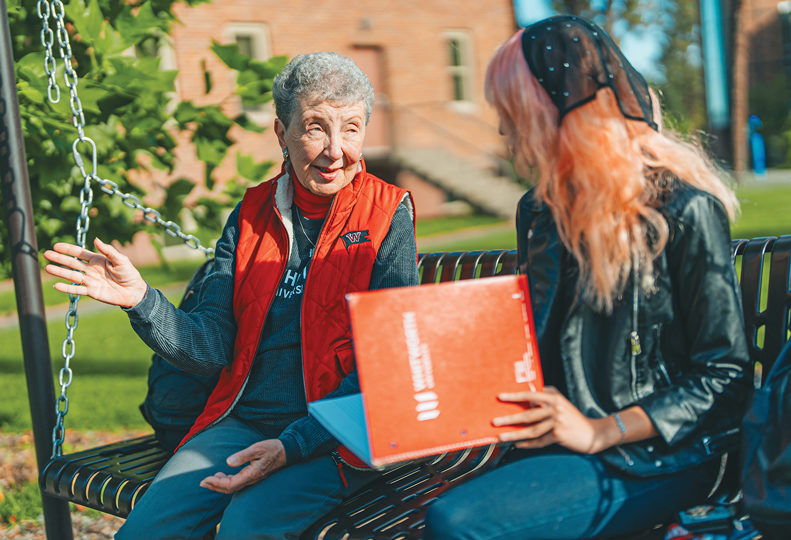 A senior woman speaks with a student on campus at Whitworth University